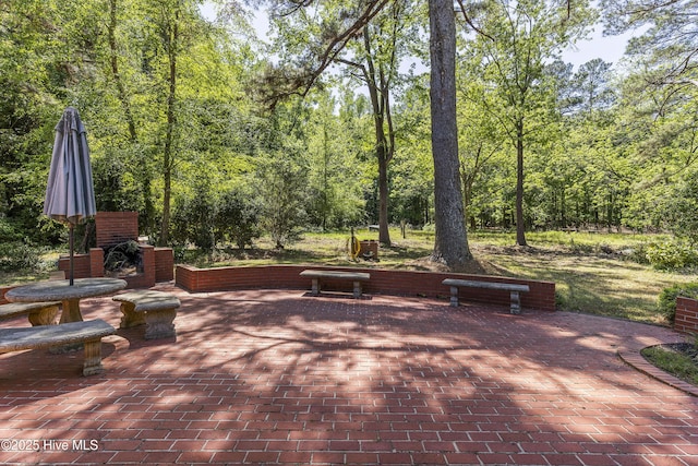 view of patio / terrace with a view of trees and an outdoor brick fireplace