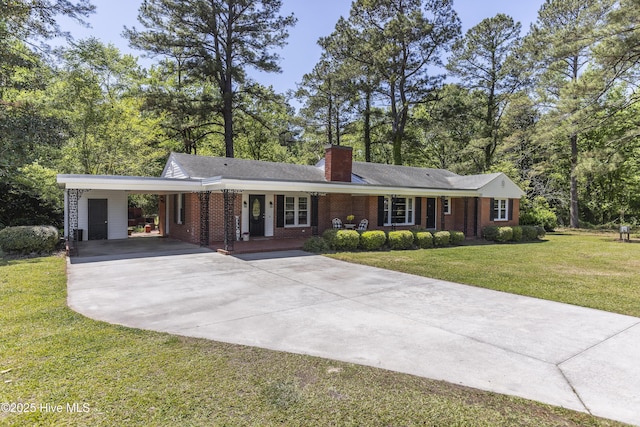 ranch-style house featuring a chimney, driveway, a carport, a front yard, and brick siding