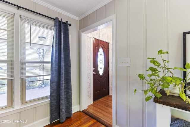 foyer entrance with baseboards, crown molding, dark wood-type flooring, and plenty of natural light