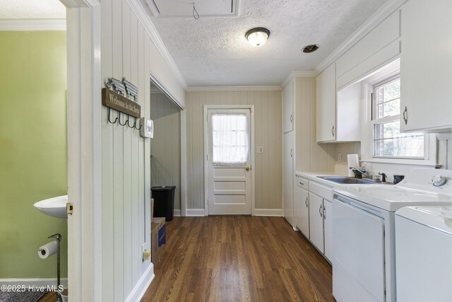 laundry room featuring plenty of natural light, dark wood-style floors, washer and clothes dryer, ornamental molding, and cabinet space