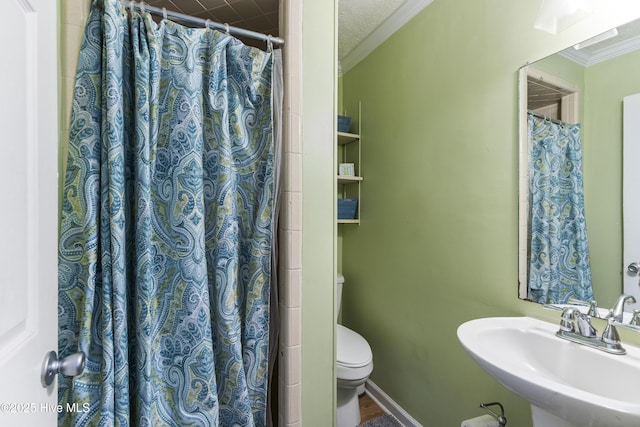 bathroom featuring a shower with shower curtain, crown molding, toilet, and a sink
