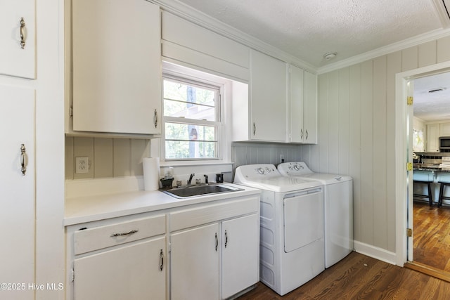 washroom featuring dark wood finished floors, ornamental molding, a sink, separate washer and dryer, and cabinet space