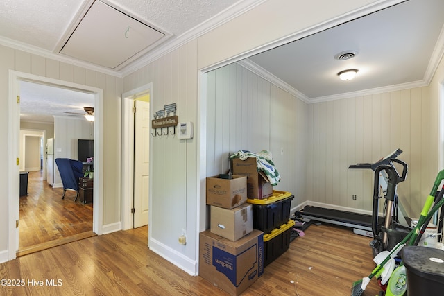 exercise room featuring attic access, crown molding, wood finished floors, and visible vents