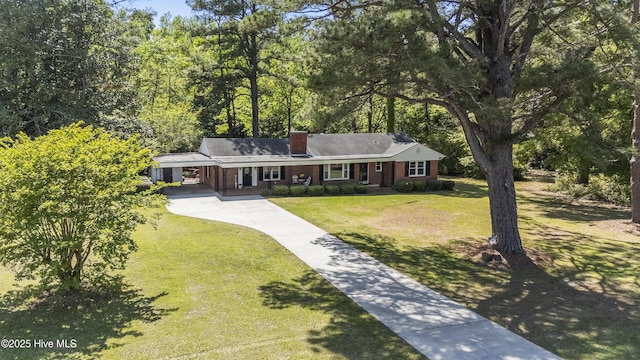 ranch-style home with a carport, a chimney, concrete driveway, brick siding, and a front yard