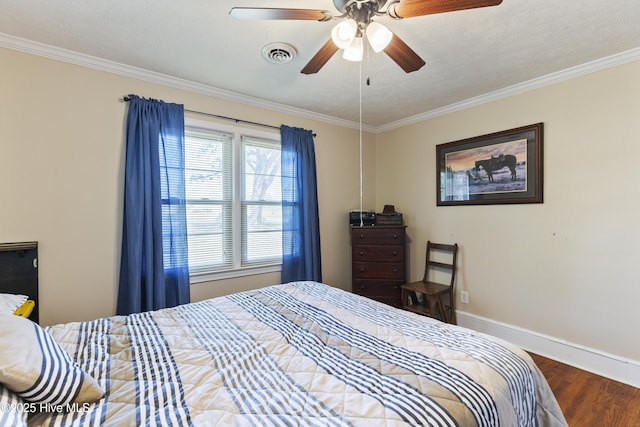 bedroom featuring baseboards, ornamental molding, wood finished floors, and visible vents