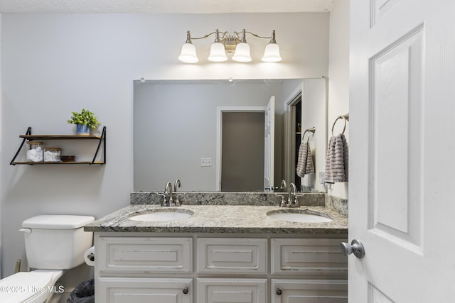 bathroom with toilet, a sink, and double vanity
