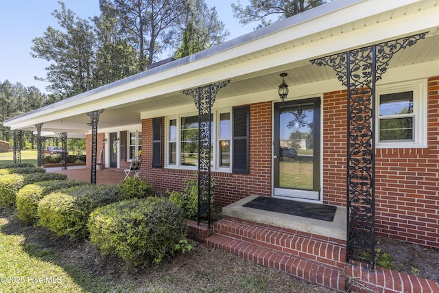 property entrance with covered porch and brick siding