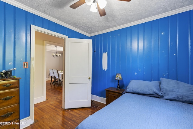 bedroom featuring baseboards, crown molding, wood finished floors, and a textured ceiling