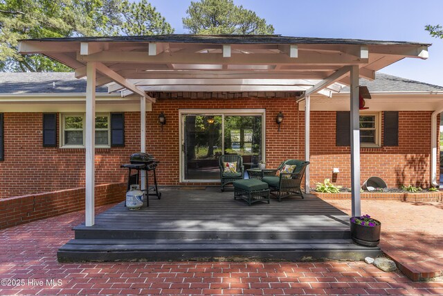 rear view of house with a wooden deck, an outdoor hangout area, brick siding, and a shingled roof