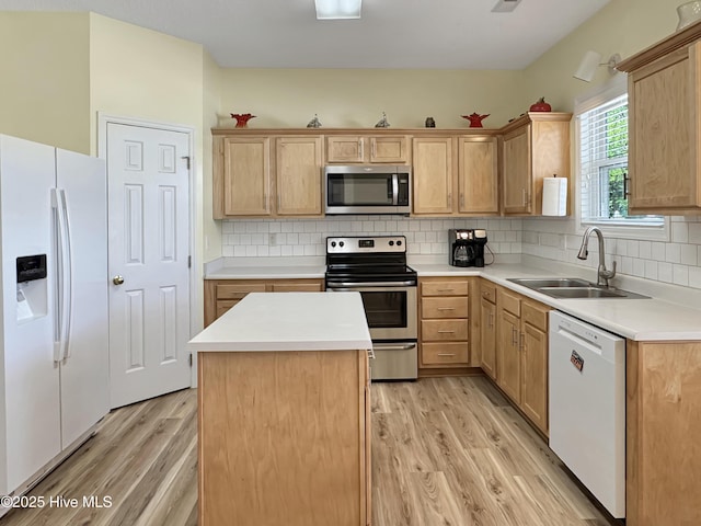 kitchen featuring appliances with stainless steel finishes, a sink, light wood-style flooring, light brown cabinetry, and backsplash