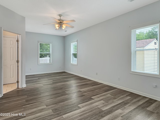 spare room with a ceiling fan, dark wood-style floors, and baseboards