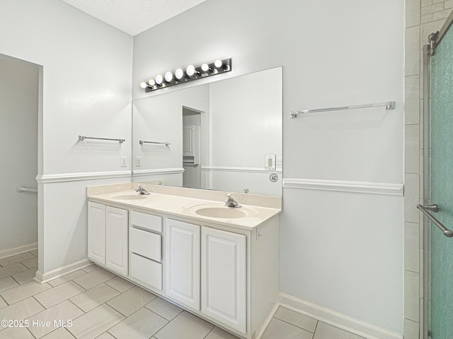 bathroom with double vanity, tile patterned floors, baseboards, a shower with door, and a textured ceiling