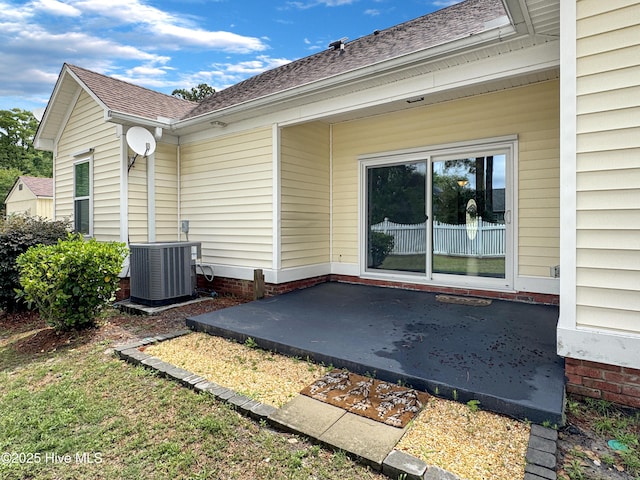 back of house with a patio area, central AC, and roof with shingles
