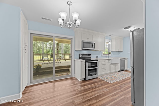 1450 State Camp Rd, Vanceboro, NC 28586 - kitchen with stainless steel appliances, a chandelier, light countertops, light wood-type flooring, and white cabinetry
