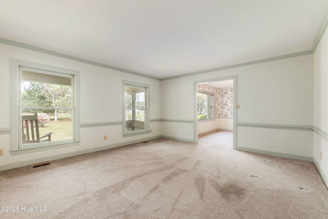 carpeted spare room featuring baseboards, ornamental molding, and visible vents