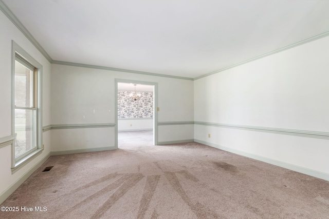 spare room featuring visible vents, crown molding, baseboards, a chandelier, and carpet flooring