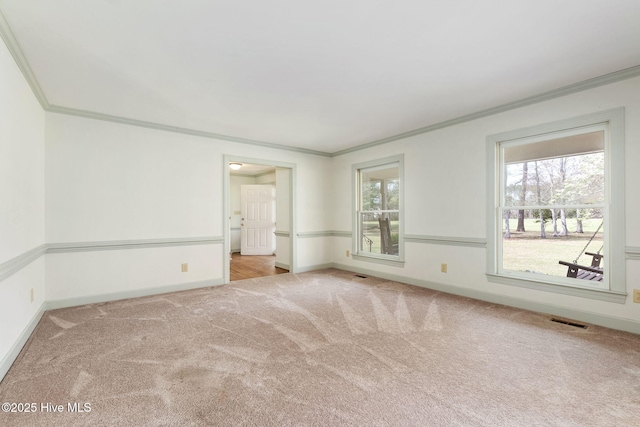 spare room featuring visible vents, carpet flooring, baseboards, and crown molding
