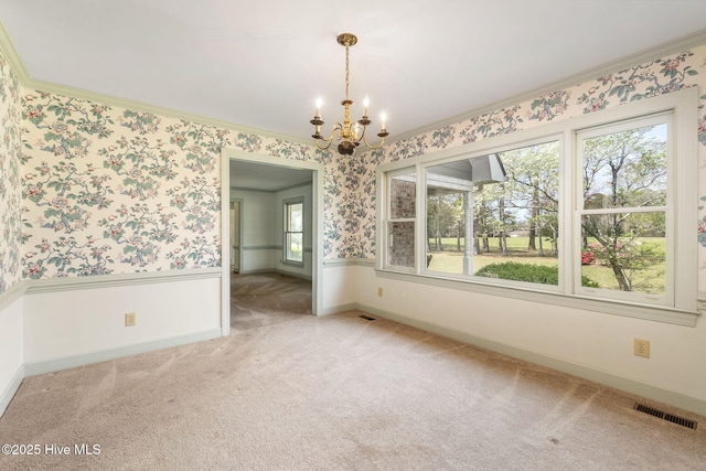 unfurnished dining area featuring crown molding, light colored carpet, a notable chandelier, wallpapered walls, and visible vents