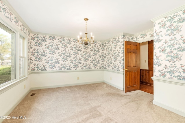 spare room with an inviting chandelier, light carpet, wainscoting, and wallpapered walls