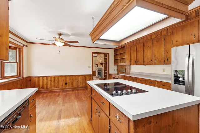 kitchen featuring wainscoting, ceiling fan, brown cabinets, and black appliances