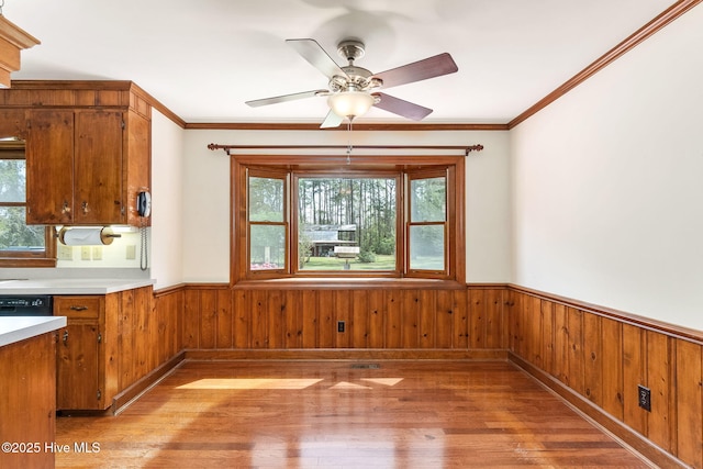 kitchen featuring wainscoting, a ceiling fan, brown cabinetry, and light wood-type flooring