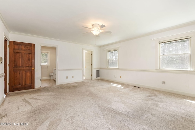 unfurnished room with carpet floors, a ceiling fan, baseboards, visible vents, and ornamental molding