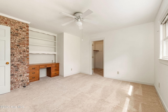 unfurnished bedroom with carpet flooring, a ceiling fan, baseboards, and a walk in closet