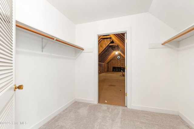 walk in closet with vaulted ceiling and carpet