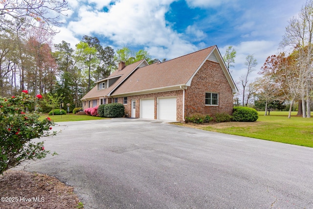 view of home's exterior featuring a chimney, a lawn, a garage, brick siding, and aphalt driveway