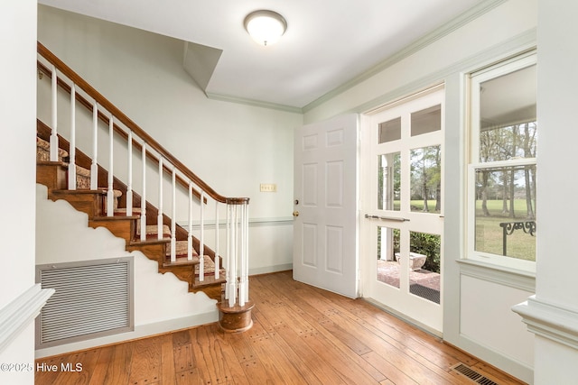 entryway with crown molding, visible vents, hardwood / wood-style flooring, and stairs