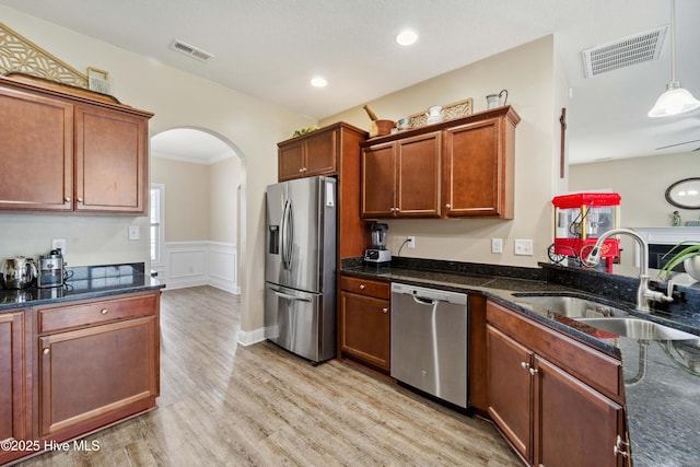 313 March Sea Ln, Jacksonville, NC 28546 - kitchen with stainless steel appliances, a sink, arched walkways, dark stone counters, and a wainscoted wall
