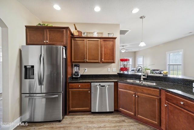 313 March Sea Ln, Jacksonville, NC 28546 - kitchen with stainless steel appliances, a sink, arched walkways, light wood-style floors, and hanging light fixtures