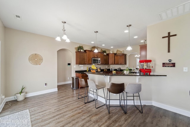 313 March Sea Ln, Jacksonville, NC 28546 - kitchen with stainless steel microwave, arched walkways, light wood-style flooring, and recessed lighting