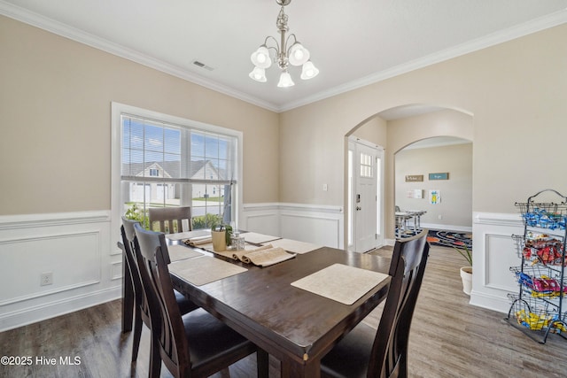 313 March Sea Ln, Jacksonville, NC 28546 - dining space featuring a chandelier, arched walkways, wood finished floors, ornamental molding, and a wainscoted wall