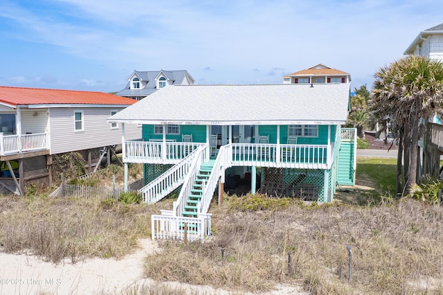 3325 W Beach Dr, Oak Island, NC 28465 - coastal inspired home with stairway, a shingled roof, and a deck