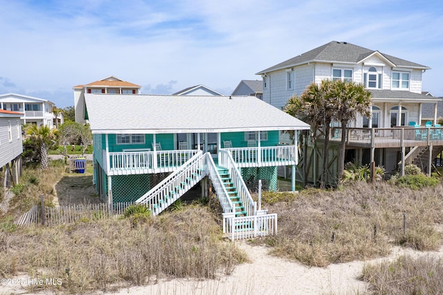 3325 W Beach Dr, Oak Island, NC 28465 - view of front of property featuring stairway, a wooden deck, and a shingled roof
