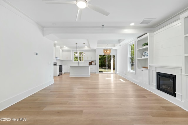 unfurnished living room featuring ceiling fan with notable chandelier, a glass covered fireplace, visible vents, recessed lighting, and baseboards