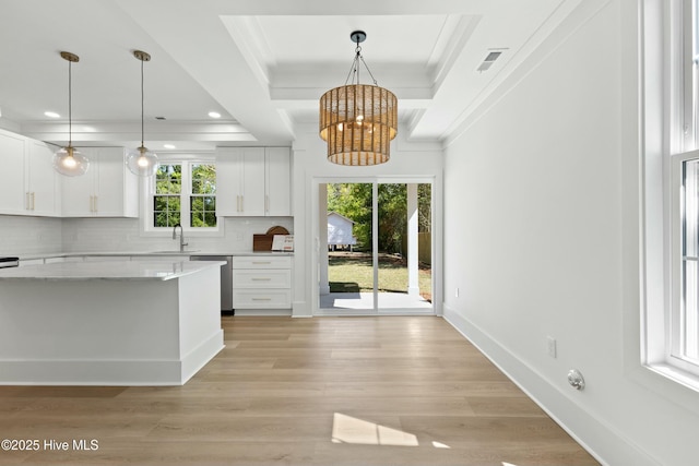kitchen featuring a notable chandelier, white cabinetry, a sink, and decorative backsplash
