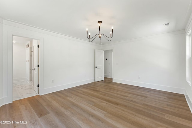 interior space with a chandelier, light wood finished floors, baseboards, and ornamental molding