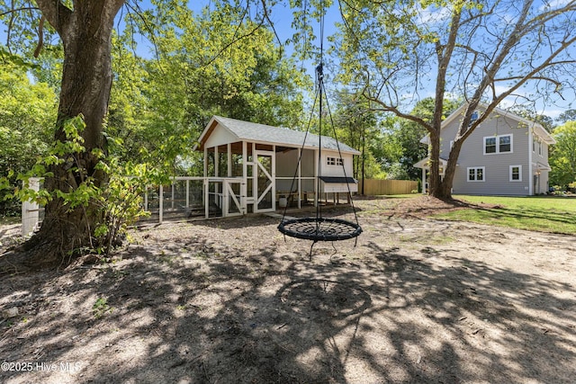 rear view of house featuring fence and an outdoor structure