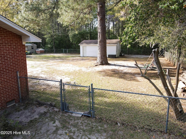 view of yard featuring a detached garage, fence, a storage shed, and a gate