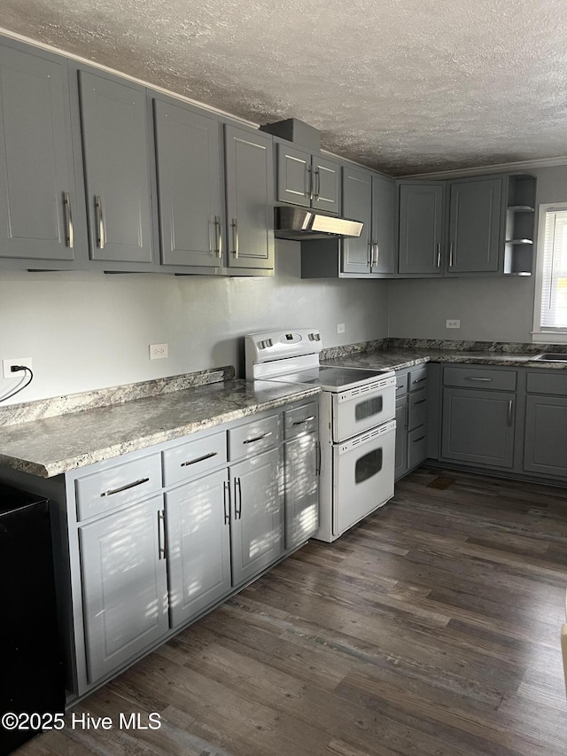 kitchen with dark wood-type flooring, a textured ceiling, gray cabinets, under cabinet range hood, and double oven range