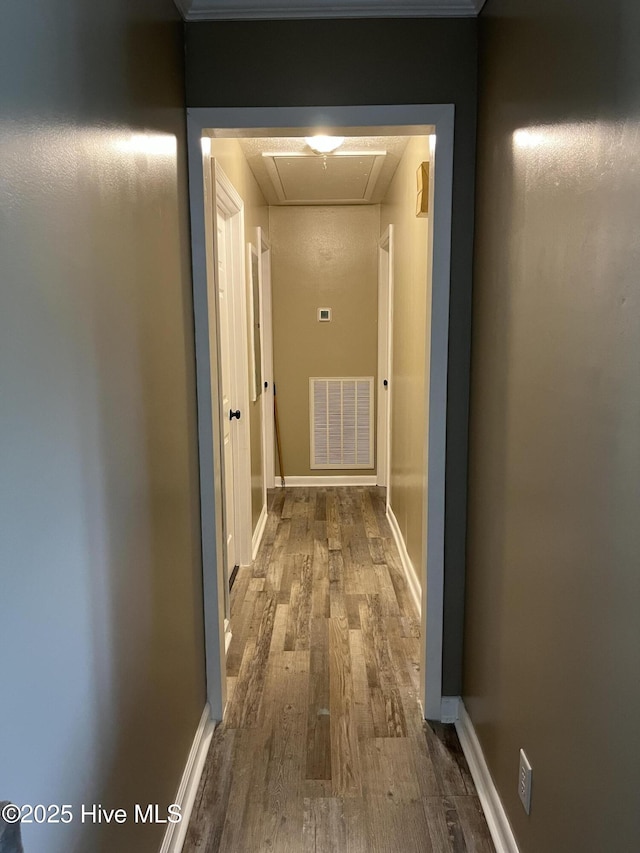 hall featuring visible vents, attic access, baseboards, and wood finished floors