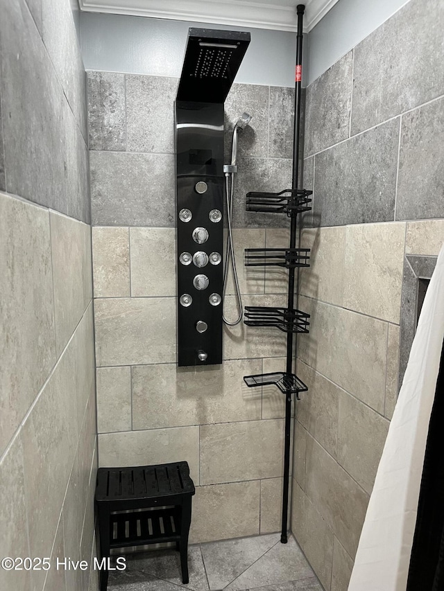 bathroom with ornamental molding and tiled shower