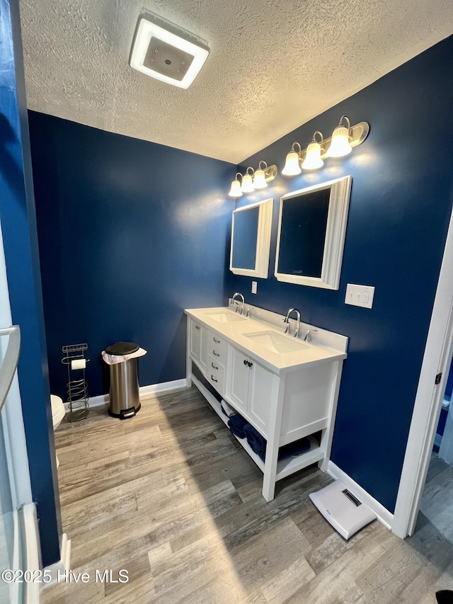 bathroom featuring visible vents, a sink, a textured ceiling, and wood finished floors