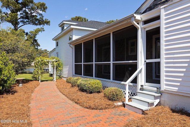 view of property exterior with entry steps and a sunroom