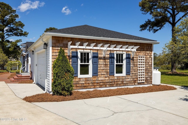 view of home's exterior featuring an attached garage, driveway, a shingled roof, and a pergola
