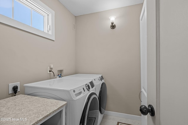 washroom featuring baseboards, washer and dryer, laundry area, and light tile patterned flooring