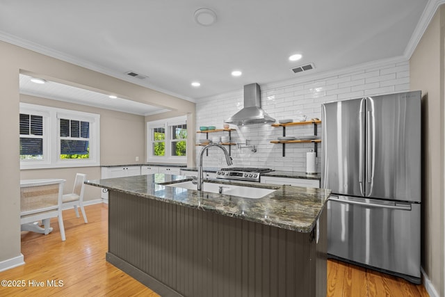 kitchen featuring visible vents, decorative backsplash, freestanding refrigerator, and wall chimney range hood