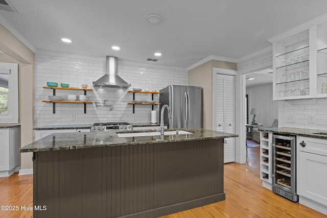 kitchen with wine cooler, freestanding refrigerator, visible vents, wall chimney range hood, and open shelves
